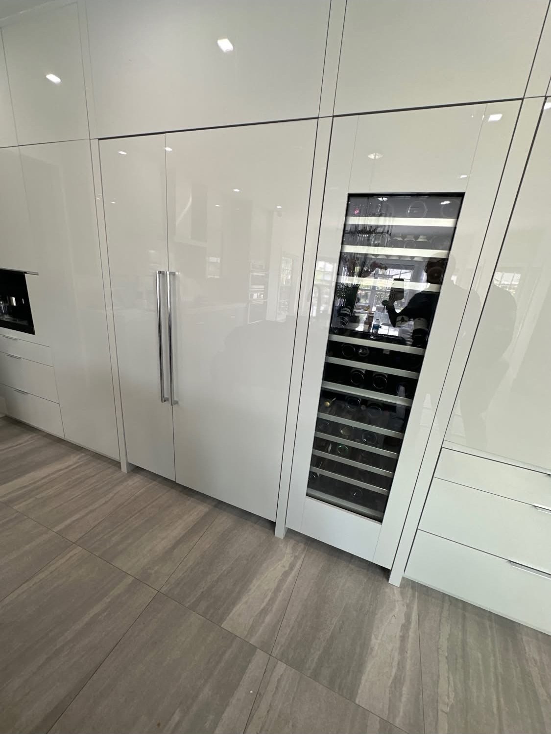 Integrated refrigerator and wine column in glossy white cabinetry